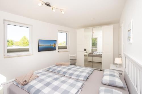 ein weißes Schlafzimmer mit einem Bett und Fenstern in der Unterkunft Ferienwohnung Sundblick in Altefähr
