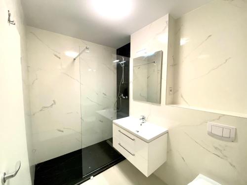 a white bathroom with a sink and a shower at Velvet Home in Timişoara