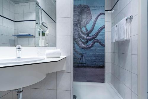 a bathroom with a sink and a shower with an octopus mural at Seminaris Hotel Potsdam Griebnitzsee in Potsdam