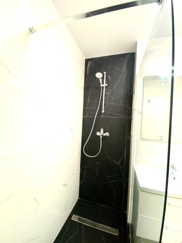 a bathroom with a shower and a black wall at Velvet Home in Timişoara