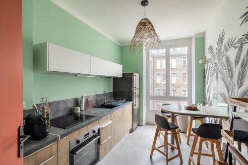 une cuisine avec des murs verts et une table et des chaises dans l'établissement Le Reef - Pépite dans l'Intramuros, à Saint-Malo