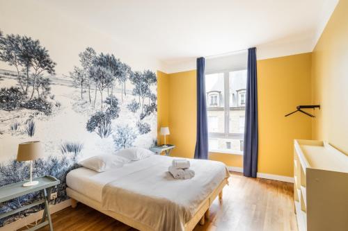 a bedroom with a large bed with yellow walls at Le Reef - Pépite dans l'Intramuros in Saint Malo