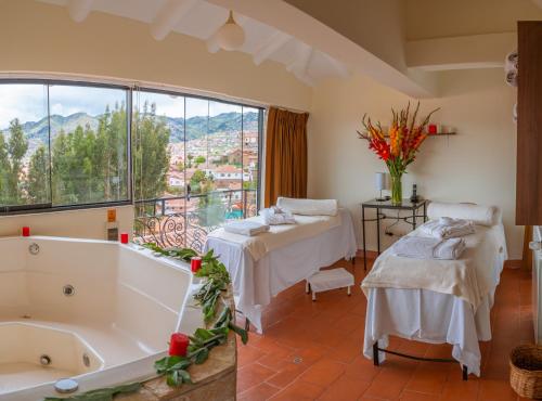 a bathroom with two beds and a tub and a window at Hotel Encantada Casa Boutique Spa in Cusco