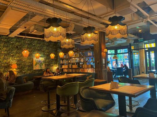 a restaurant with tables and chairs and chandeliers at House Belfast Hotel in Belfast