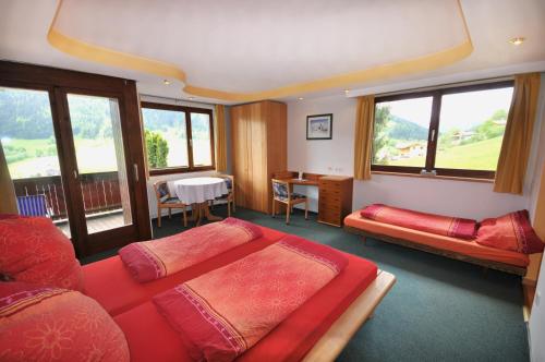a bedroom with two beds and a desk and windows at Auhof in Niederau