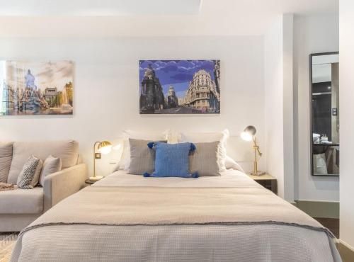a bedroom with a large bed with three paintings on the wall at Cibeles I in Madrid
