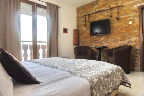 1 dormitorio con 1 cama y TV en una pared de ladrillo en Eke Irin Apartments en Ohrid