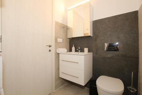 a bathroom with a white toilet and a sink at Sunset Sea View Villa 1 in Agios Georgios