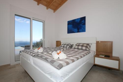 a bedroom with a large bed with a large window at Sunset Sea View Villa 1 in Agios Georgios