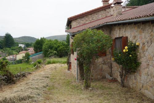 a stone house with flowers on the side of it at La Puerta de Gredos in San Martín del Pimpollar