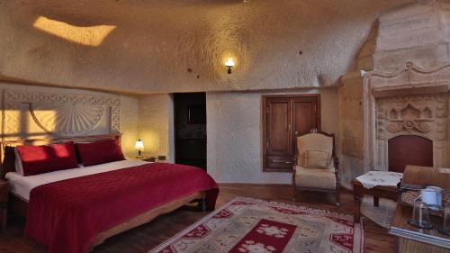 a bedroom with a bed with red sheets and a chair at Vezir Cave Suites in Goreme