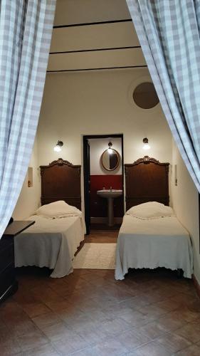 two beds in a room with a sink and a mirror at B&B del Giglio in Cefalù