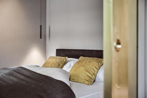 a bed with two gold pillows on top of it at Stufels 7 Design Apartment with Brixen Card in Bressanone