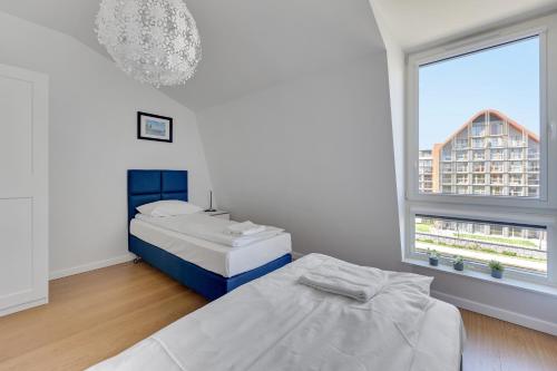 a white room with two beds and a window at GRANO FLATS Gdańsk - RiverFront Apartment in Gdańsk