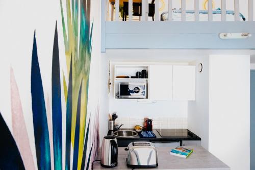 une petite cuisine avec un évier et un micro-ondes dans l'établissement Le Duplex Carmes, à Toulouse