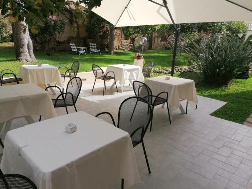 een patio met witte tafels en stoelen en een parasol bij Cosmo Rooms a pochi passi da Tropea in Santa Domenica