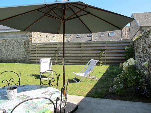 a table and chairs under an umbrella in a yard at Holiday Home La Lucerie - BAY402 by Interhome in Bretteville-sur-Ay