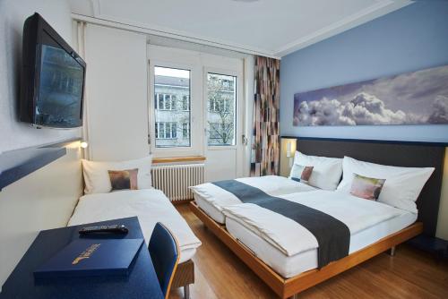 a hotel room with two beds and a tv at Hotel Bristol Zurich in Zürich
