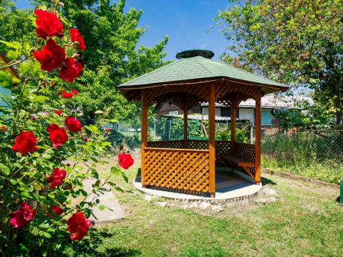 a gazebo in a garden with red roses at Holiday Home Amaryllis by Interhome in Balatonakarattya