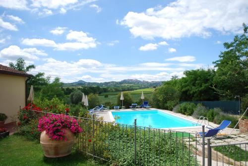 einen Pool in einem Garten mit Blumen und einem Zaun in der Unterkunft Agriturismo Il Cantastorie in Montepulciano