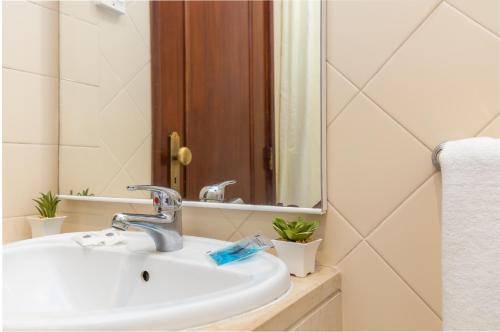 W łazience znajduje się umywalka i lustro. w obiekcie Hotel Residencial Colibri w Costa de Caparica