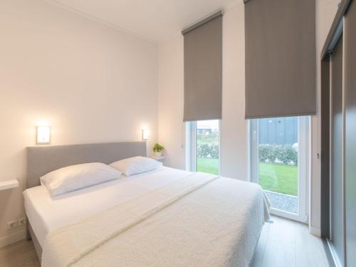 a white bedroom with a large bed and a window at Holiday Home Ruisweg 45 by Interhome in Wemeldinge