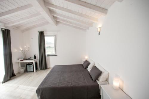 a white bedroom with a bed and a window at Dolce Dormire Suite in Arcola