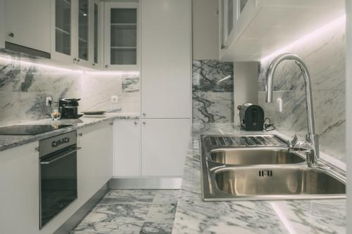 a kitchen with a stainless steel sink and white cabinets at Casas da Tapada in Lisbon