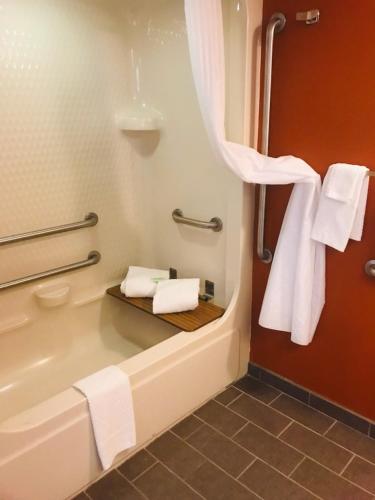 a bathroom with a tub with towels and a sink at Sleep Inn North Charleston Ashley Phosphate in Charleston