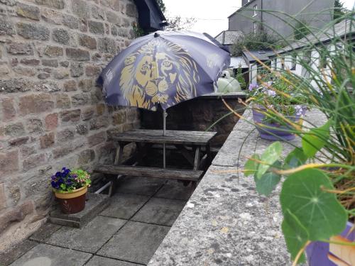 an umbrella sitting on a bench next to a brick wall at Beautiful 1-Bed Cottage in Trellech in Trelleck