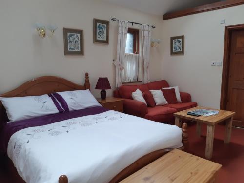 a bedroom with a bed and a red couch at Beautiful 1-Bed Cottage in Trellech in Trelleck