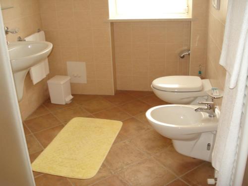 a bathroom with two toilets and a sink and a mirror at Agriturismo Parco Del Chiese in bedizzol