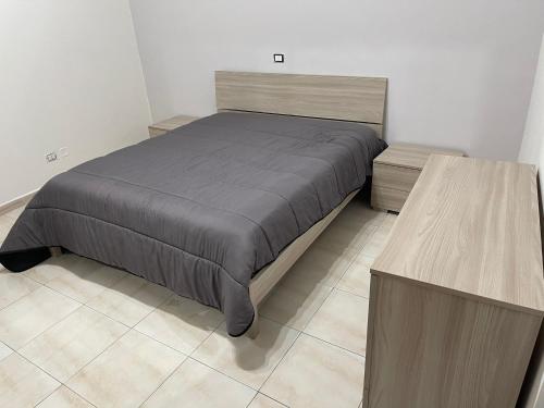 een slaapkamer met een bed en 2 houten tafels bij A Casa di Mimia in Avellino