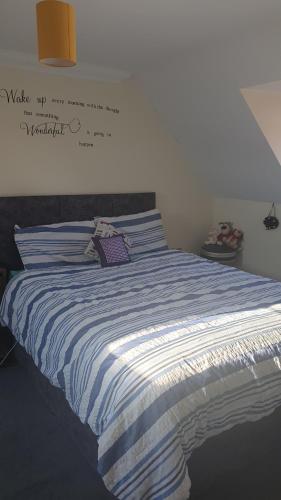 a bed with a blue and white striped blanket at SUNSHINE ROOM in Colchester
