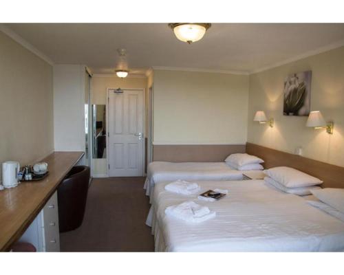 a hotel room with two beds and a desk at Diamond Hotel in Torquay
