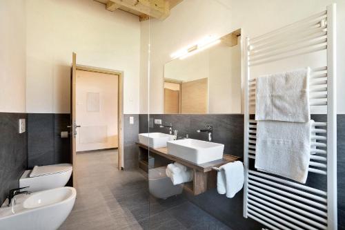 Un baño con dos lavabos, un inodoro y un espejo. en Unterötzbauerhof - Fewo Rosenblick, en Tirolo