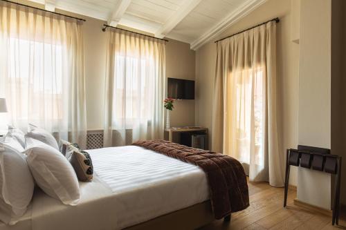 a bedroom with a bed with white sheets and windows at Hotel Porta San Mamolo in Bologna