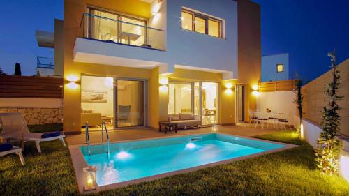a villa with a swimming pool in front of a house at Tessera Villas & Studios Collection in Gouvia