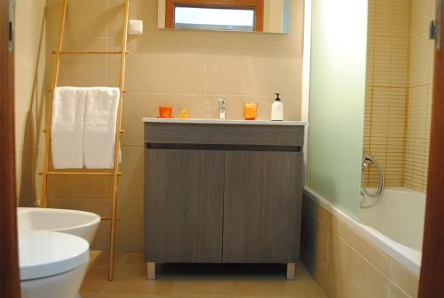 a bathroom with a sink and a toilet and a tub at Apartamentos Gharb Diem in Tavira