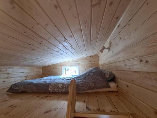 a bed in a log cabin with a wooden ceiling at Siedlisko nr 4E i 4F nad jeziorem Skarlińskim, jezioro, mazury, domki letniskowe, bania in Kurzętnik