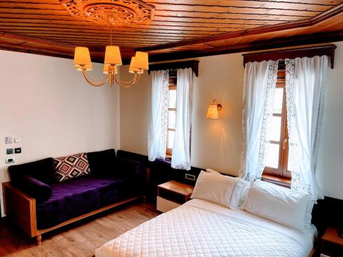 a bedroom with a bed and a couch and windows at KERCULLA Resort in Gjirokastër