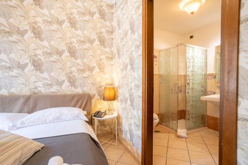a bedroom with a bed and a bathroom with a shower at Locanda Da Otello in Marta