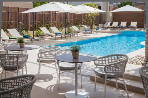 a patio with tables and chairs next to a pool at Hotel Torino Wellness & Spa in Diano Marina