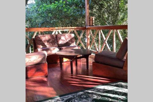 a patio with two chairs and a table on a deck at Caoni Riverside Suites - Birders Paradise by the river, Ecuadorian Chocó in Puerto Quito