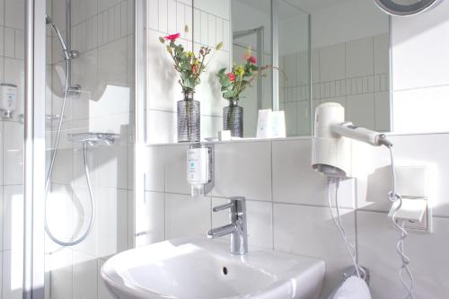 La salle de bains blanche est pourvue d'un lavabo et d'un miroir. dans l'établissement Astenturm Hotel, à Winterberg