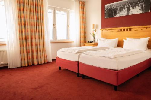 two beds in a hotel room with red carpet at Astenturm Hotel in Winterberg