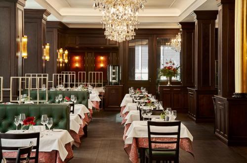 a dining room with tables and chairs and a chandelier at Eden Hotel Wolff in Munich