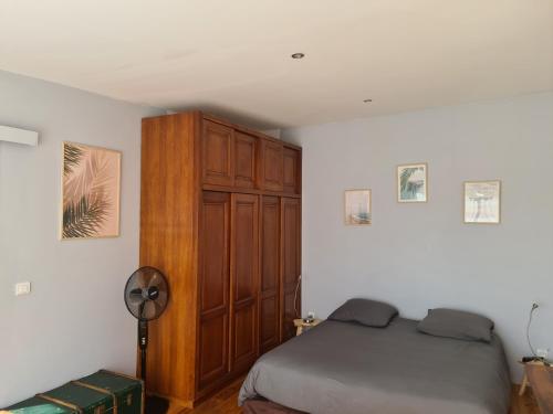 een slaapkamer met een bed en een houten kast bij Dépendance Spacieuse & Cosy Entre et Mer avec Spa in Landéda