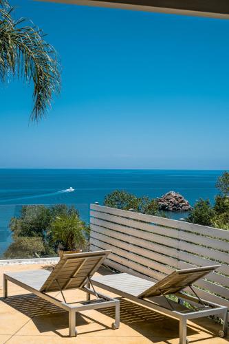 two chairs sitting next to a bench with the ocean at A Tonnara in Cefalù