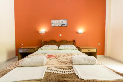 1 dormitorio con paredes de color naranja y 1 cama con 2 mesas en Villa Kostas, en Vitalades